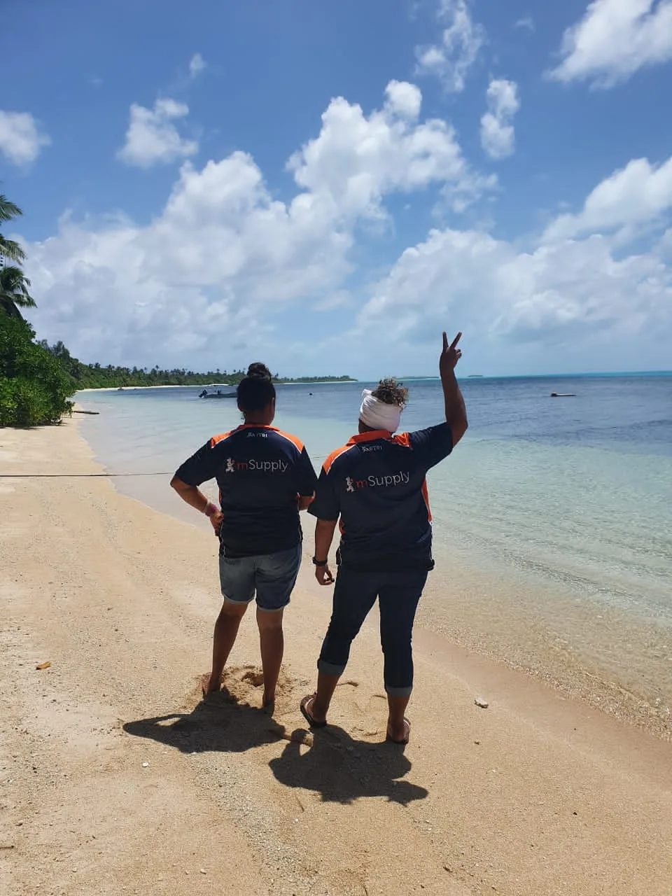 Two mSupply team members on a beach
