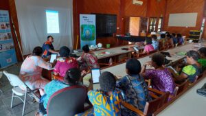 Group of women in a building facing a projected screen in a training session for Tamanu. 